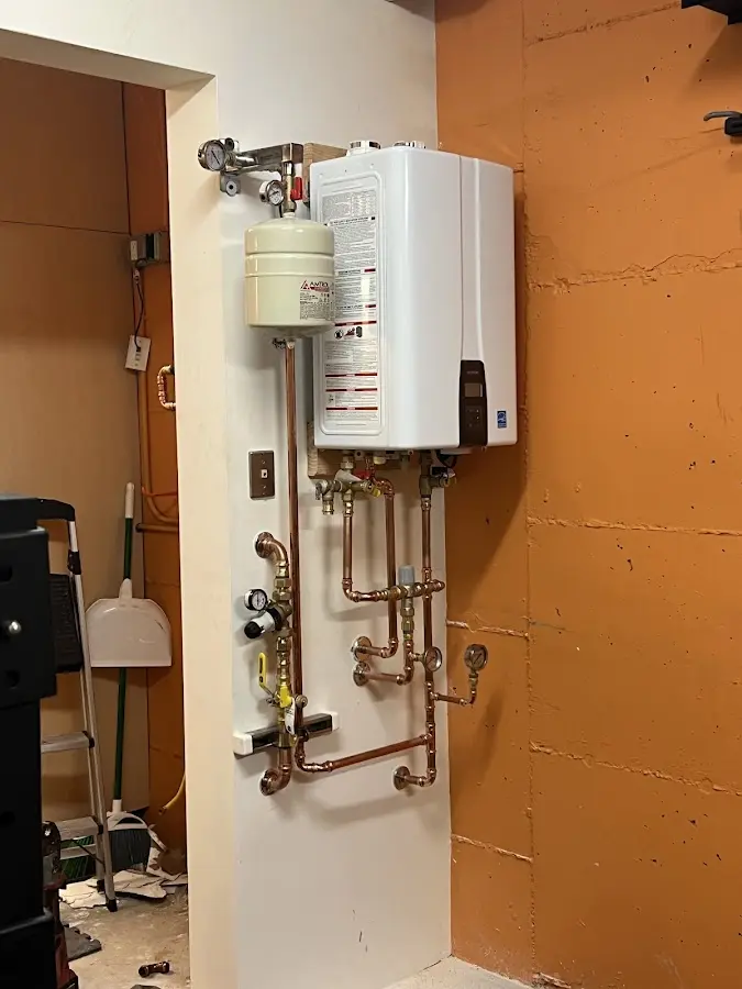 Plumbing technician inspecting water heater connections in Mendham